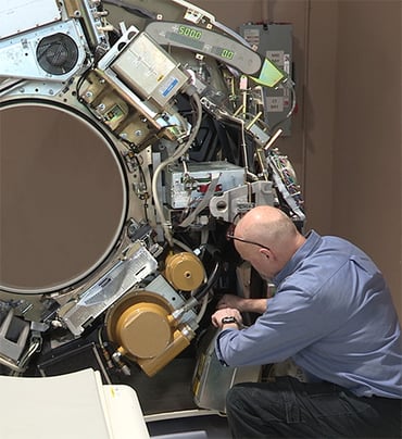 An engineer replaces parts on a CT machine